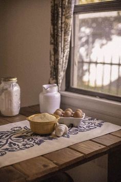 eggs and flour on a table in front of a window