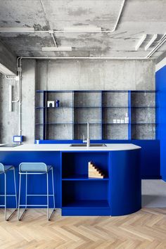 a kitchen with blue cabinets and stools next to a counter top that has shelves on it