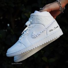 a hand holding a white nike air jordan shoe with chains attached to it's side