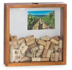 a wooden frame filled with wine corks on top of a white wall next to a painting