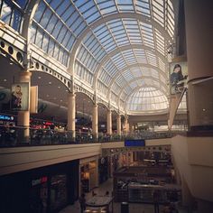 the inside of a shopping mall filled with lots of windows and people walking through it