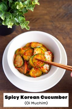 a person holding chopsticks in a bowl of food with the words spicy korean cucumber