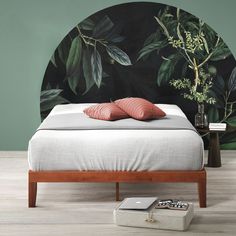 a bedroom with a green wall and white bed in front of a plant covered headboard