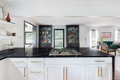 a kitchen with white cabinets and black counter tops