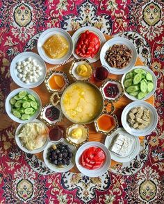 a table topped with bowls filled with different types of food next to each other on top of a rug