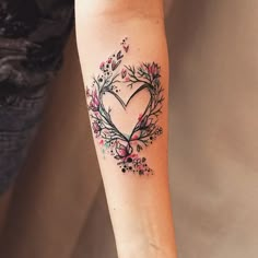 a woman's arm with a heart shaped tattoo on the left side of her arm