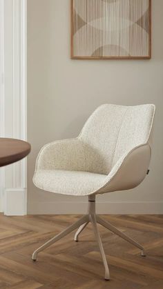 a white chair sitting on top of a hard wood floor next to a wall mounted painting