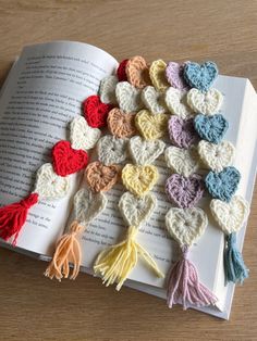 an open book with crocheted hearts and tassels on top of it