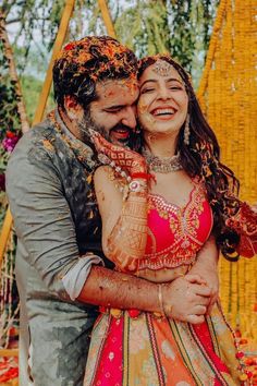 a bride and groom hugging each other in front of an orange backdrop at their wedding