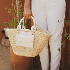 Handmade by craftswomen from our rural cooperative DOUM FOR WOMEN, our totes are made with impeccable craftsmanship and from high quality materials. Basket carryall bag as the perfect summer staple. Fresh, light and versatile tote with a rather rustic feel and a market vibe, ideal for strolling around in style from the beach to the city. This handwoven basket crafted from palm leaves is enriched with high-end classic vegan leather details, an exterior pocket and a removable canvas pouch with a z Luxury Straw Bucket Bag For Daily Use, Designer Luxury Straw Beach Bag, Luxury Summer Straw Bag For Market, Luxury Straw Shoulder Bag For The Beach, Luxury Chic Straw Bag For Everyday Use, Luxury Straw Bag For Vacation, Luxury Summer Straw Beach Bag, Luxury Square Straw Travel Bag, Luxury Summer Bags For Everyday Use