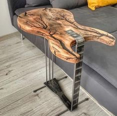 a wooden table sitting on top of a metal stand in front of a gray couch