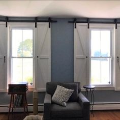 a living room filled with furniture and windows covered in shades of blue, grey and white