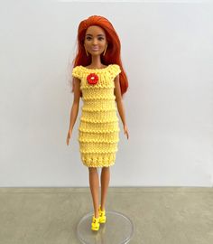 a doll with red hair wearing a yellow crochet dress and bright yellow shoes