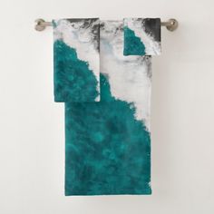 two towels hanging on a towel rack in front of a white wall with blue and green paint