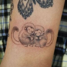 a tattoo on the arm of a person with two monkeys in front of a butterfly