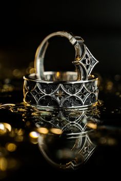 two wedding rings sitting on top of each other in front of a black background with gold circles