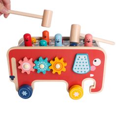 a wooden toy truck with lots of toys on it's side and a person holding a hammer