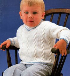 a little boy sitting in a chair wearing a sweater