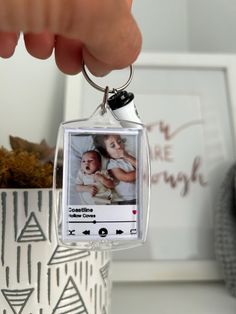 a hand holding a keychain with an image of a baby in the frame