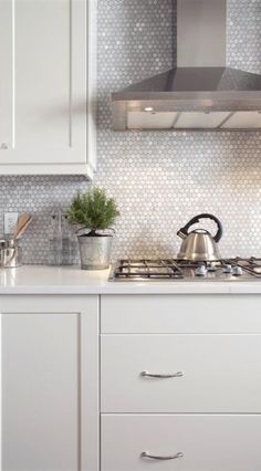 a stove top oven sitting inside of a kitchen next to white cupboards and drawers