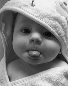 a black and white photo of a baby wrapped in a towel looking at the camera