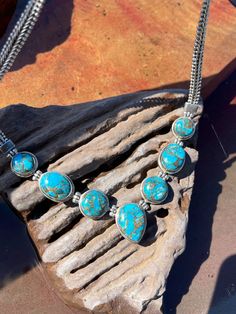 "Nicely made sterling silver turquoise necklace bezel set with 7 pieces of turquoise in a blue-bronze color.  4 round turquoise pieces, 2 oval pieces and center stone shape is pear.  The chain is heavy Byzantine style measuring in width at 6.46mm.  The length of necklace is 17\".  The clasp is a heavy box and tongue with a figure 8 safety.  Beautifully put together and stunning on. 62.9 grams." Southwestern Oval Turquoise Necklace, Southwestern Blue Cabochon Necklaces, Southwestern Blue Cabochon Necklace, Southwestern Style Blue Cabochon Necklace, Blue Turquoise Necklace, Heavy Chain, Valley View, Bib Necklaces, Figure 8