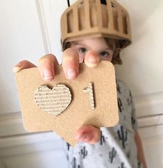 a young boy holding up a cardboard cutout with the number one on it