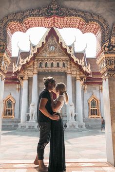 a man and woman are standing in front of a building with ornate designs on it