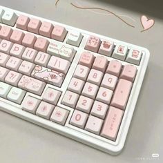 a pink keyboard with hello kitty keys and hearts drawn on the keys, sitting on a table