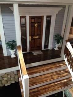 a house with stairs leading up to the front door and entry way, as well as potted plants