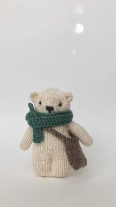 a white teddy bear with a green scarf around it's neck, sitting in front of a white background