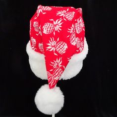 "This novelty Santa hat is made up in a Christmas red and white tropical pineapple print cotton fabric. Hawaiian fabric hat is decorated with a snowy white faux Sherpa fur fabric trim. Put Santa in a tropical island mode for that balmy warm holiday season. The sizing on the hat is generous and will fit most adult head sizes. The styling is a slouch cone, traditional Santa look. There is a snowy white pompom stitched on the top. Opening measurement is 24-25\" circumference, tapering in cone style Casual White Hat For Holiday, Casual White Holiday Hat, Casual White Christmas Hat, White Christmas Holiday Hat, Christmas Luau, Las Vegas Christmas, Christmas Red And White, White Island, Hawaiian Fabric