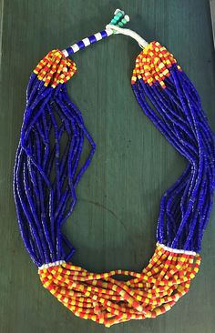 "Gorgeous vintage African glass trade bead statement necklace. It has 20 strands of glass trade beads with stunning cobalt blue, red, and yellow colors. Unique clasp featuring turquoise color beads. Necklace Measures 25\"." Festival Blue Beaded Necklaces With Colorful Beads, Artisan Blue Beaded Necklaces For Festivals, Traditional Blue Faceted Beads, Traditional Hand-strung Blue Necklace, Blue Beaded Necklaces For Festivals, Traditional Faceted Beads For Festival, Traditional Blue Beaded Necklaces With Colorful Beads, Artisan Blue Beaded Necklace With Tiny Beads, Traditional Large Blue Beads