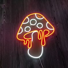 a neon sign with a mushroom on it sitting on a wooden floor next to a wall