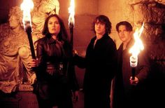 three people holding torches in front of a statue