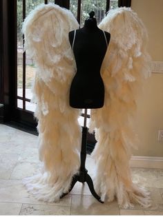 two mannequins dressed in white feathers on a display stand next to a window