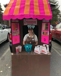 a woman standing in front of a pink and orange food cart with pumpkins on it