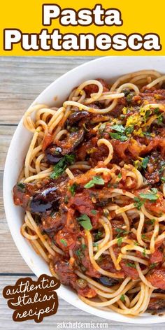 pasta with tomato sauce and olives in a white bowl on top of a wooden table