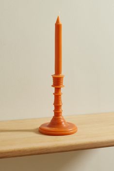 an orange candle sitting on top of a wooden table