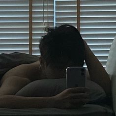 a man laying in bed looking at his cell phone