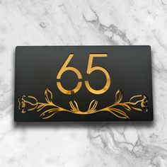 a black and gold sign with the number 55 on it sitting on a marble surface