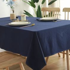 a blue table cloth with two plates on it and some flowers in the vase next to it