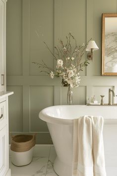 a white bath tub sitting in a bathroom next to a sink and mirror on the wall