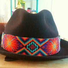 a black hat with colorful beading on it sitting on top of a wooden table