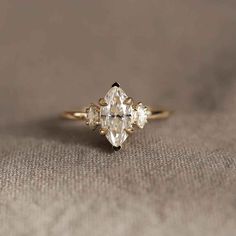 an engagement ring with three pear shaped diamonds on the front and side, set in yellow gold