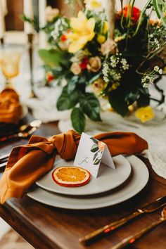 an orange slice on a plate with napkins and flowers in the background at a wedding reception