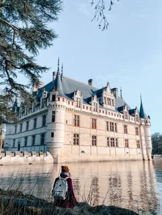 a woman is standing in front of a castle