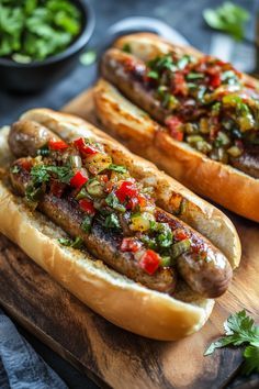 two hot dogs on buns covered in toppings and sitting on a cutting board