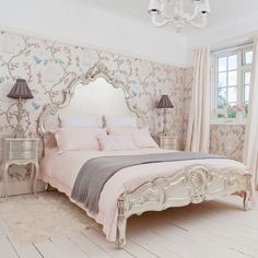 a white bed sitting in a bedroom next to a window