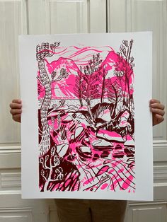 a person holding up a pink and black print